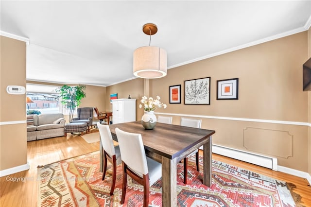 dining space with hardwood / wood-style flooring, a baseboard radiator, and ornamental molding