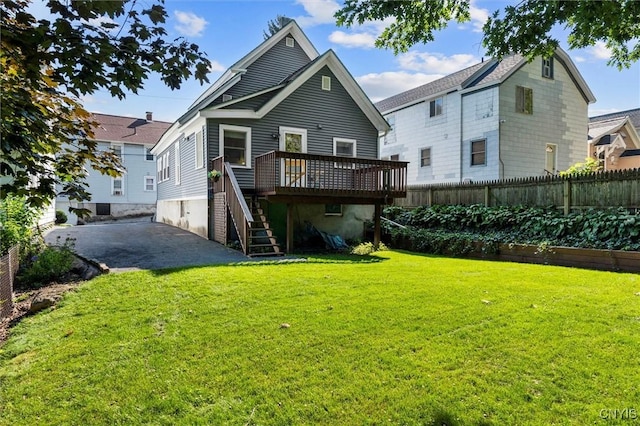 rear view of property featuring a deck and a lawn