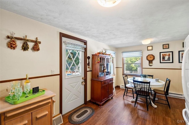 dining room featuring a baseboard heating unit, dark hardwood / wood-style floors, and a textured ceiling