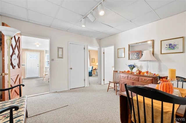 hallway featuring rail lighting, a paneled ceiling, and light colored carpet