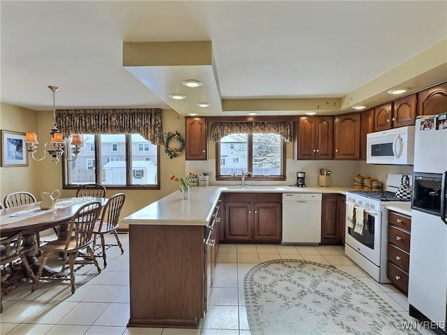 kitchen with pendant lighting, sink, white appliances, and light tile patterned flooring