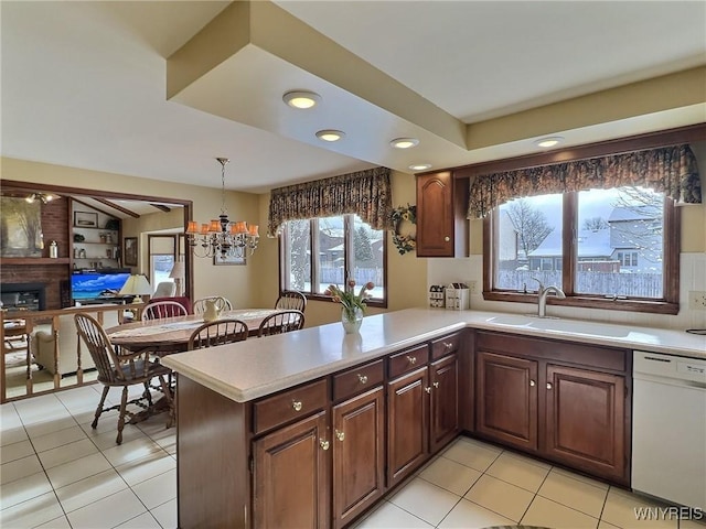 kitchen with pendant lighting, sink, light tile patterned floors, white dishwasher, and kitchen peninsula