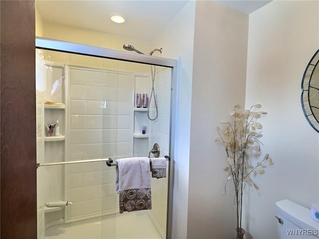 bathroom with a shower with door and toilet