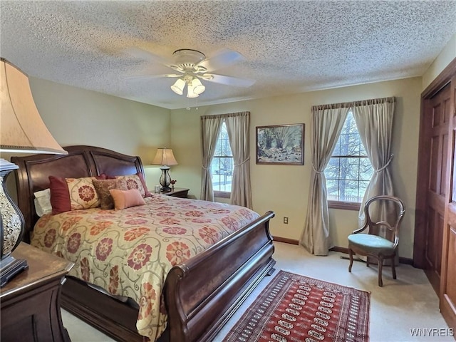 carpeted bedroom featuring ceiling fan and a textured ceiling