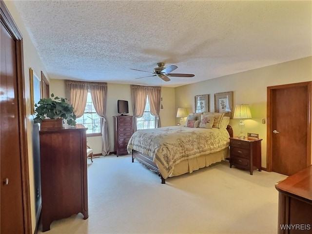 carpeted bedroom featuring ceiling fan and a textured ceiling