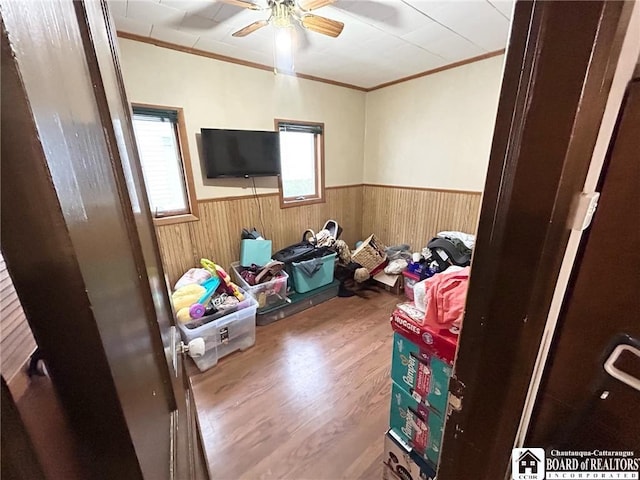 bedroom with crown molding, ceiling fan, hardwood / wood-style floors, and wood walls