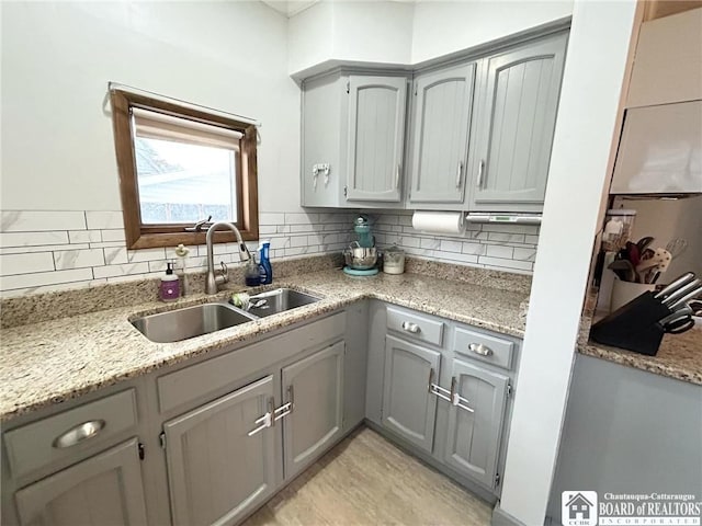 kitchen with gray cabinets, sink, and backsplash