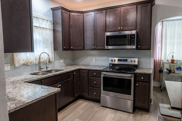 kitchen featuring sink, light wood-type flooring, plenty of natural light, stainless steel appliances, and light stone countertops