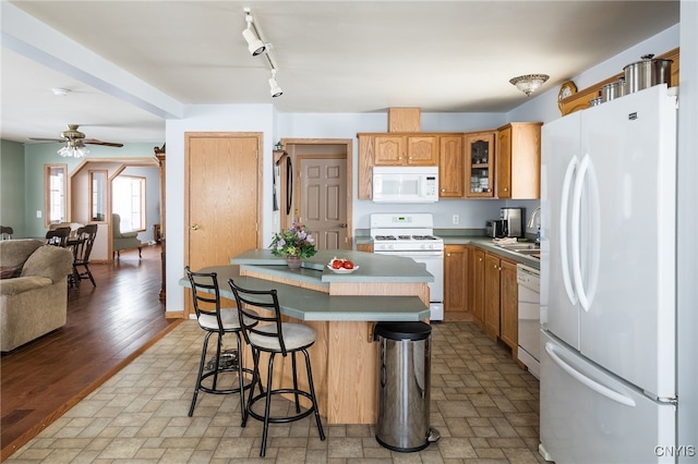 kitchen featuring a breakfast bar, sink, a center island, ceiling fan, and white appliances