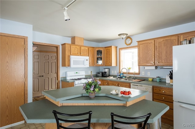 kitchen with sink, white appliances, a center island, and a kitchen bar