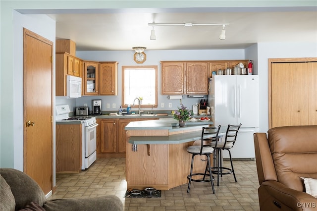 kitchen with sink, white appliances, a kitchen island, and a kitchen bar