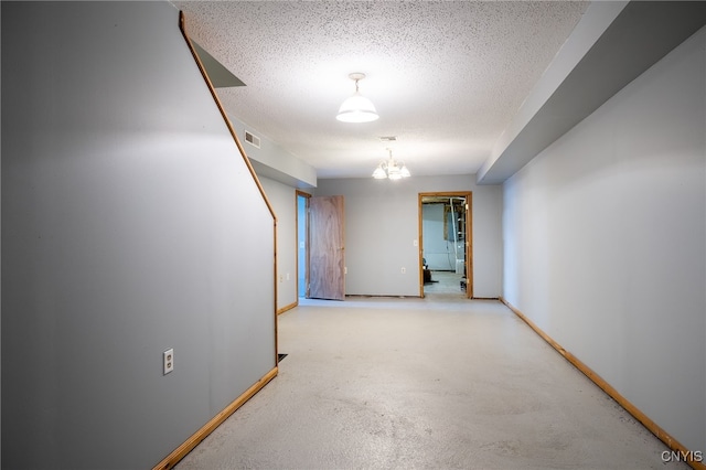 hallway featuring an inviting chandelier, light colored carpet, and a textured ceiling