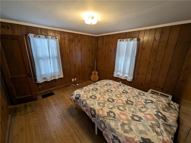 bedroom featuring crown molding, dark hardwood / wood-style flooring, and wood walls