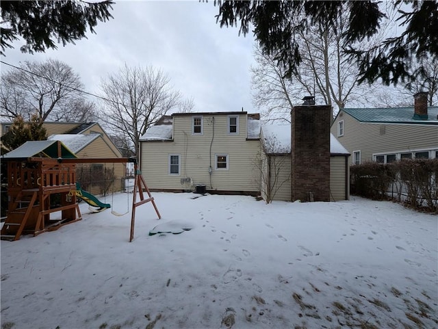 snow covered rear of property featuring a playground