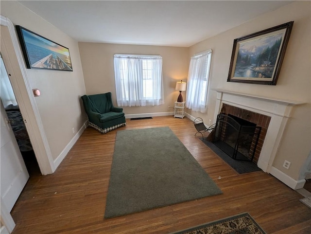 sitting room with a brick fireplace and dark hardwood / wood-style floors