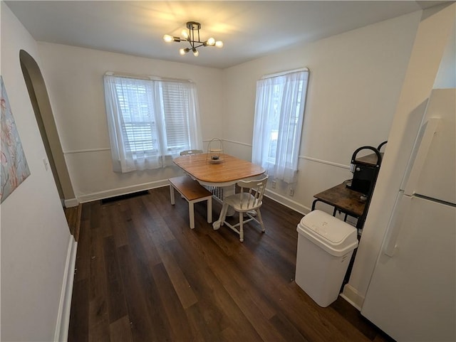 dining area with dark hardwood / wood-style flooring and a notable chandelier