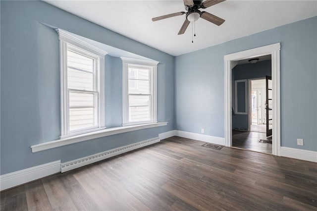 empty room with a baseboard heating unit, dark wood-type flooring, and ceiling fan