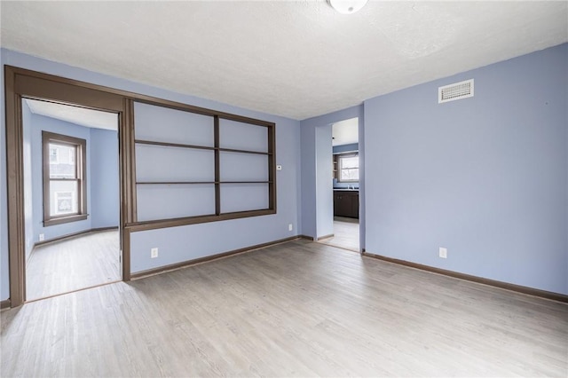 unfurnished room with light hardwood / wood-style floors and a textured ceiling