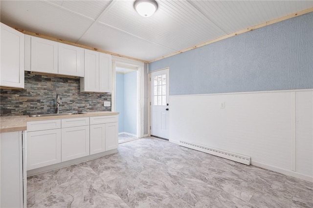 kitchen with sink, white cabinets, and baseboard heating