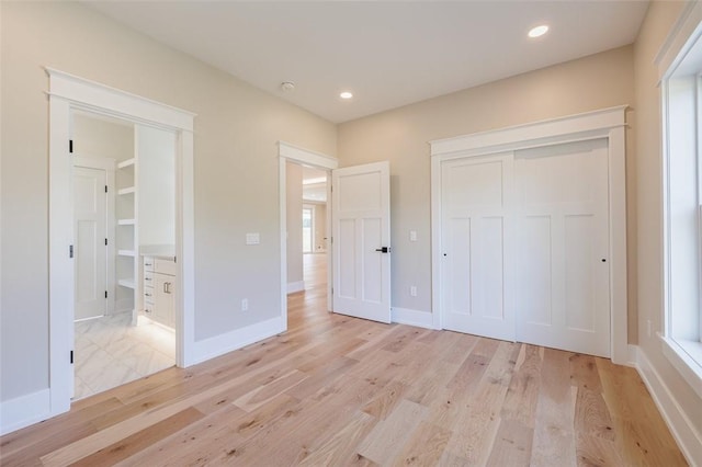 unfurnished bedroom featuring multiple windows, a closet, and light hardwood / wood-style flooring