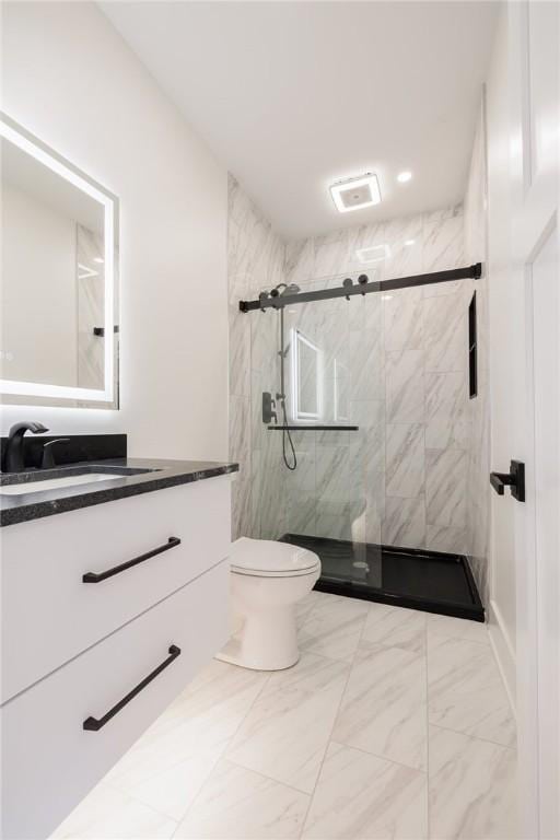 bathroom featuring vanity, a shower with shower door, and toilet