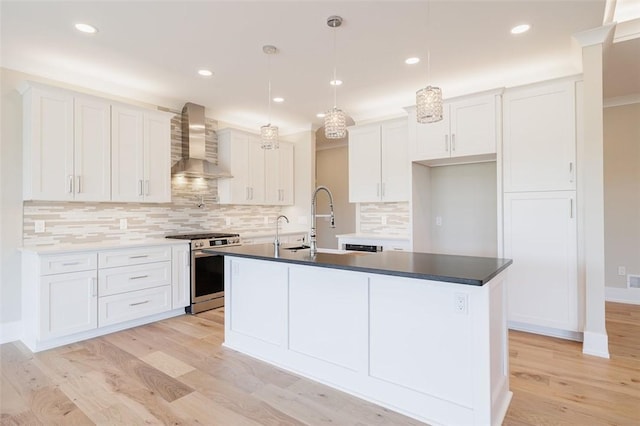 kitchen with white cabinetry, stainless steel range with gas stovetop, an island with sink, and wall chimney exhaust hood