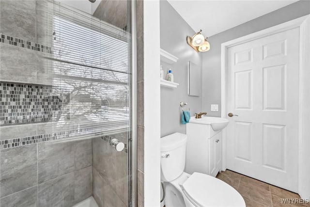 bathroom featuring tile patterned floors, vanity, toilet, and a shower with door