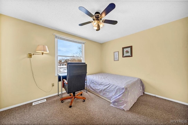 carpeted bedroom with ceiling fan and a textured ceiling