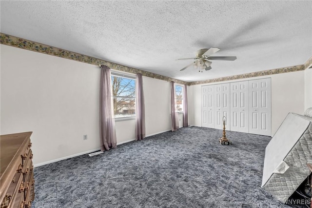 unfurnished living room featuring dark carpet, a textured ceiling, and ceiling fan