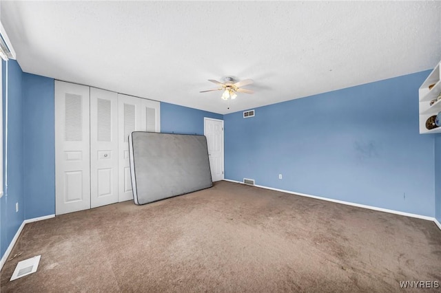 unfurnished bedroom featuring ceiling fan, dark carpet, and a textured ceiling