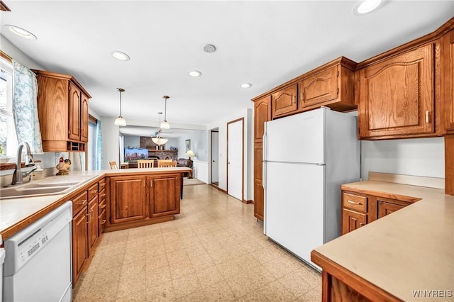 kitchen featuring hanging light fixtures, sink, white appliances, and kitchen peninsula