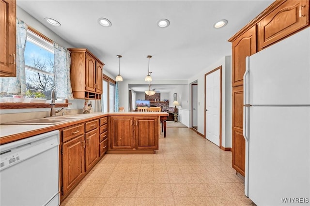 kitchen with white appliances, decorative light fixtures, kitchen peninsula, and sink