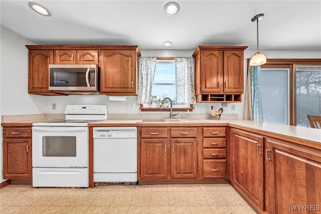 kitchen with pendant lighting, white appliances, and sink