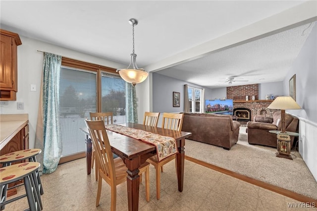 dining space with a textured ceiling, a fireplace, and ceiling fan