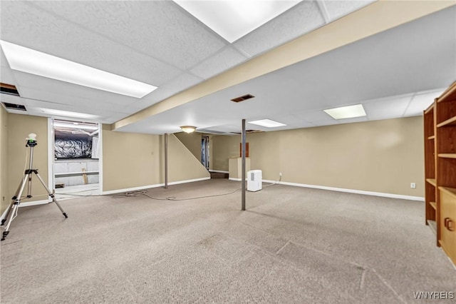 basement with a paneled ceiling and carpet floors