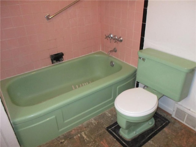 bathroom featuring tiled shower / bath and toilet