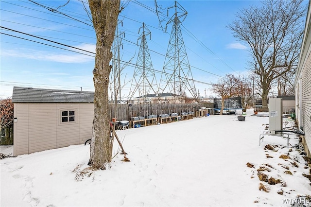 snowy yard featuring a storage unit