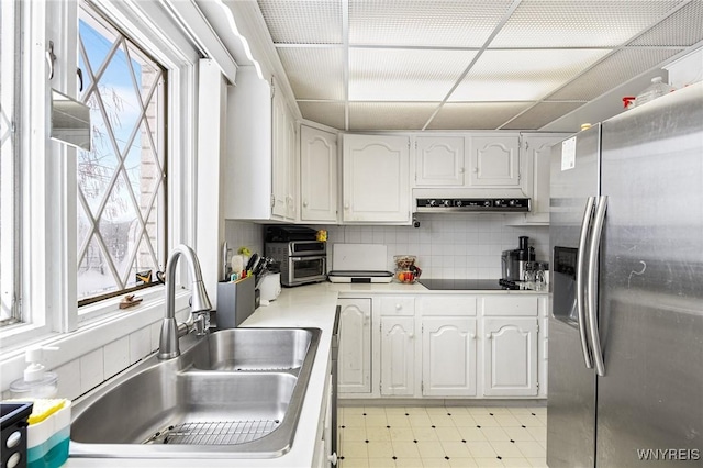 kitchen with black electric cooktop, stainless steel fridge with ice dispenser, sink, and white cabinets