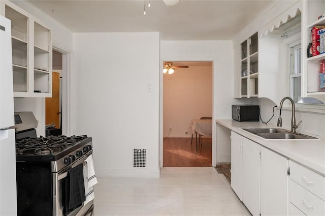 kitchen with white cabinetry, sink, light tile patterned floors, ceiling fan, and gas range