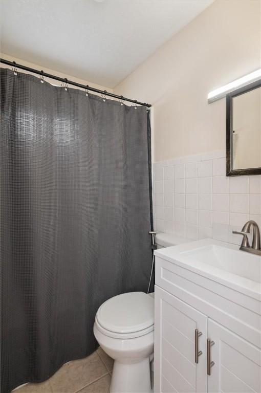 bathroom with tile patterned floors, toilet, tile walls, and vanity