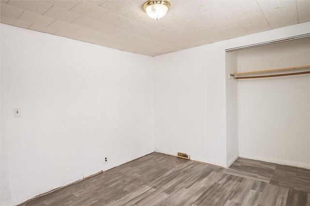 unfurnished bedroom with dark hardwood / wood-style flooring and a closet