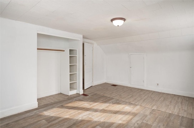 unfurnished bedroom with lofted ceiling, hardwood / wood-style floors, and a closet