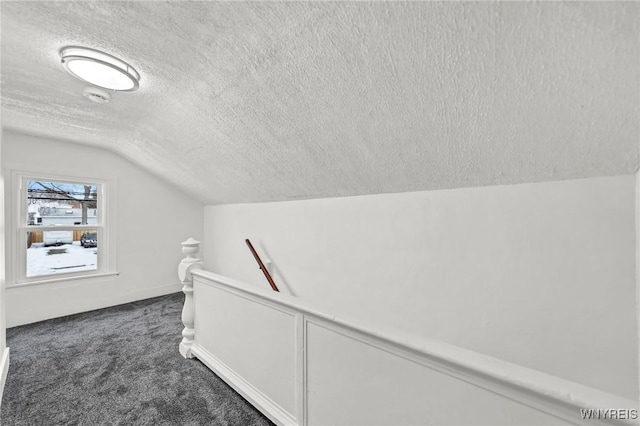 hall featuring lofted ceiling, carpet floors, and a textured ceiling