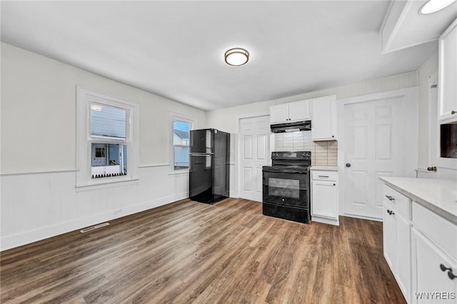 kitchen featuring white cabinetry, backsplash, dark wood-type flooring, and black appliances