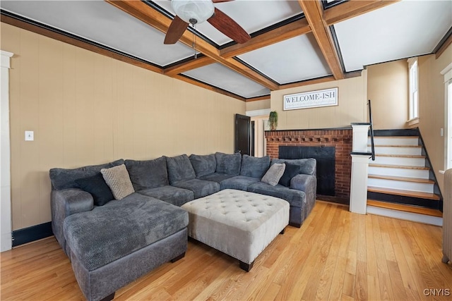 living room featuring ceiling fan, a fireplace, coffered ceiling, and light hardwood / wood-style floors