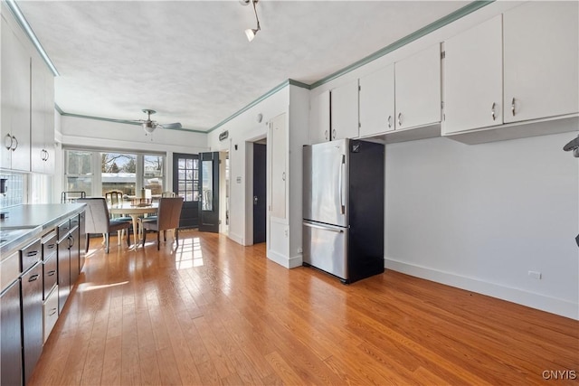 kitchen with stainless steel fridge, light hardwood / wood-style flooring, ceiling fan, white cabinetry, and ornamental molding