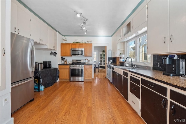 kitchen with sink, tasteful backsplash, light hardwood / wood-style flooring, appliances with stainless steel finishes, and white cabinets