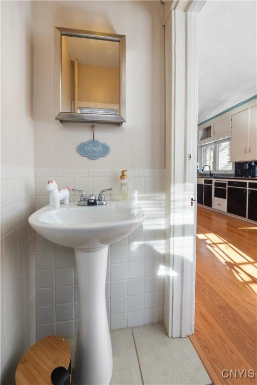 bathroom with wood-type flooring and tile walls