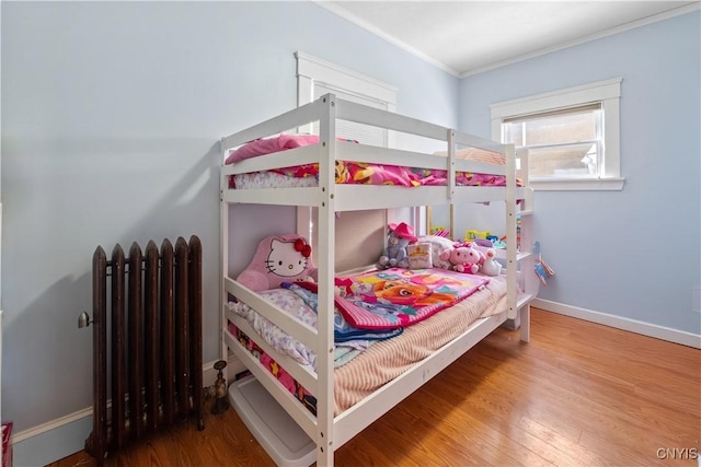 bedroom with radiator, crown molding, and wood-type flooring