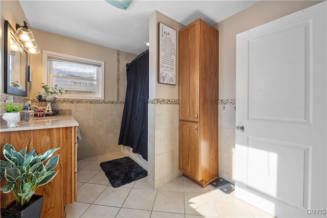 bathroom featuring tile patterned flooring, vanity, tile walls, and curtained shower